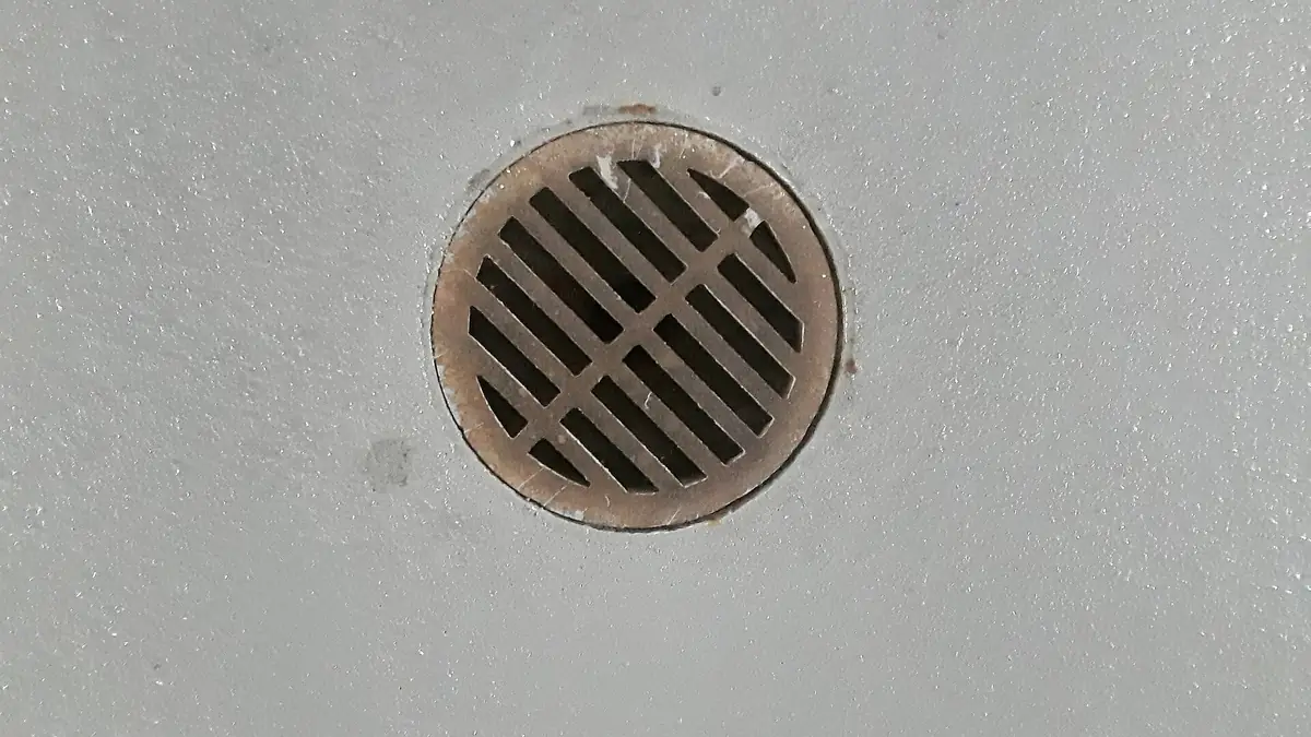 Round metal floor drain grate set in a concrete floor