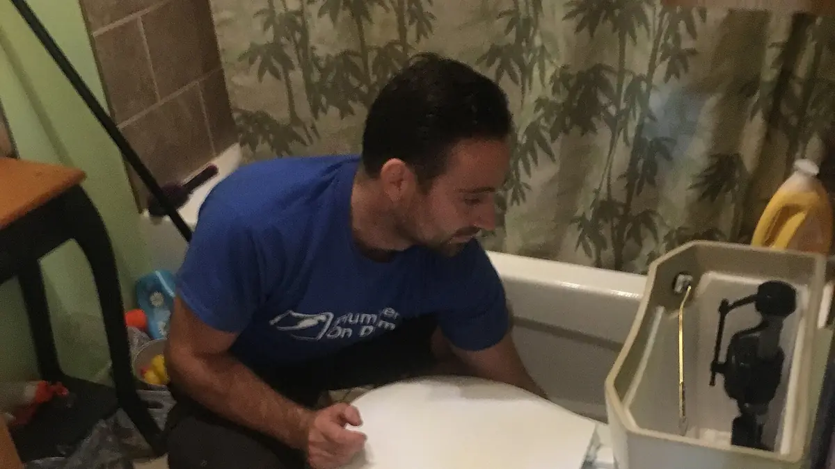 Man repairing a toilet in a bathroom